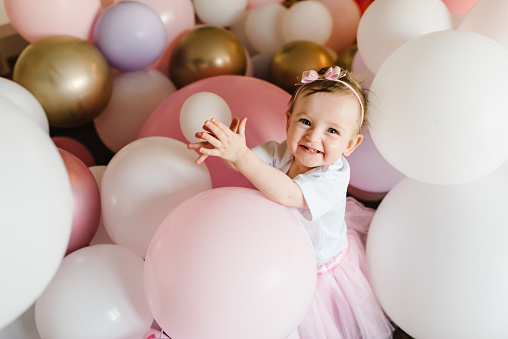 Cute baby girl 1 year play with colorful balloons in the studio. Isolated. Birthday party. Celebration. Happy birthday baby. Play room in home.