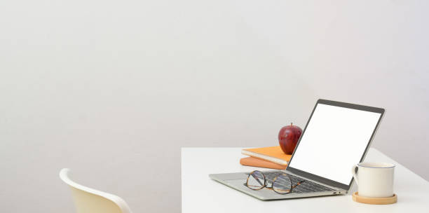 istock Minimal workplace with open laptop computer and office supplies on white desk 1170616817