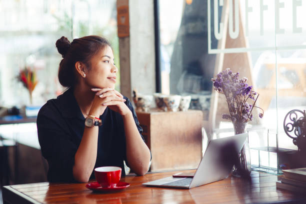 istock Asian woman working in cafe and looking out window. 1170617513