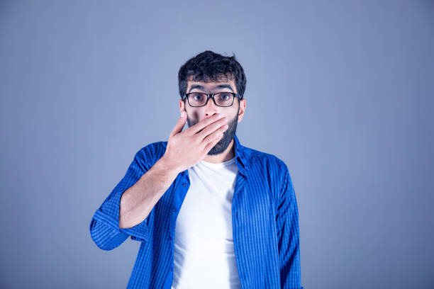 istock Surprised man closes his mouth on gray background 1170617887