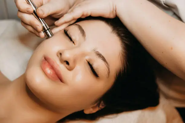 Close up of a lovely caucasian woman having microdermabrasion non invasive therapy with derma pen in a wellness center.