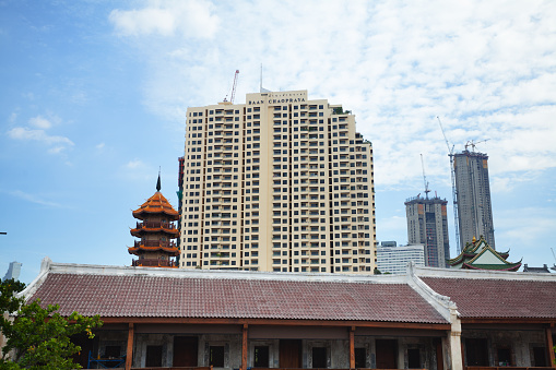 Roof of old Lhong 1919 and modern condominiums in background in Bkk. Lhong 1919 house is located in Khlong San district. Between house and modern condominiums is small tower of temple and shrine Che Chin Khor.