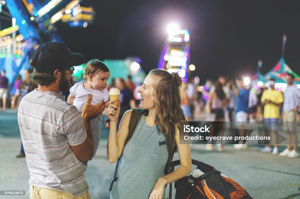 Young Millennial family enjoying their time at the Empire State Fair in Springfield MO on a hot July summer night At the Empire State Fair in Springfield Missouri a Young Milennial family including father mother and baby boy enjoying their time  on a hot July summer night (Shot with Canon 5DS 50.6mp photos professionally retouched - Lightroom / Photoshop - original size 5792 x 8688 downsampled as needed for clarity and select focus used for dramatic effect) Family Stock Photo