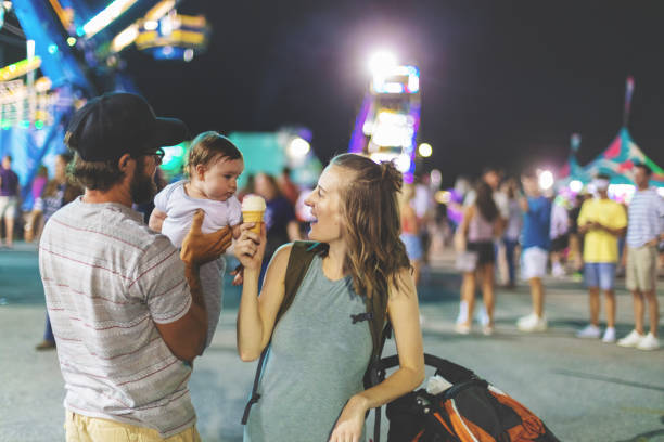 Young Millennial family enjoying their time at the Empire State Fair in Springfield MO on a hot July summer night At the Empire State Fair in Springfield Missouri a Young Milennial family including father mother and baby boy enjoying their time  on a hot July summer night (Shot with Canon 5DS 50.6mp photos professionally retouched - Lightroom / Photoshop - original size 5792 x 8688 downsampled as needed for clarity and select focus used for dramatic effect) springfield missouri photos stock pictures, royalty-free photos & images