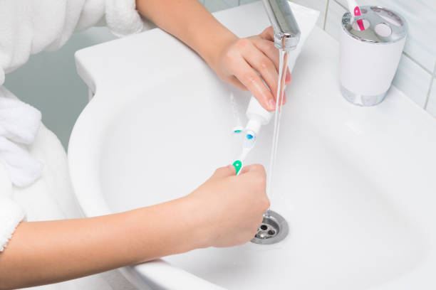 istock hands over the sink apply toothpaste to the brush, top view close-up 1170628940