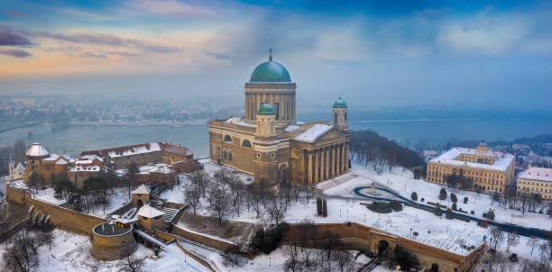 Esztergom, Hungary - Aerial panoramic view of the beautiful snowy Basilica of Esztergom with Slovakia at the background on a foggy winter morning stock photo