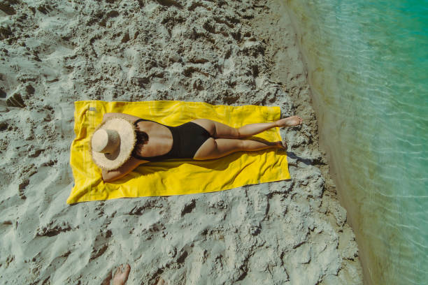 istock woman sunbathing at sand beach laying on yellow blanket 1170634107