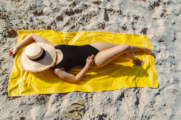 istock overhead view woman sunbathing at yellow blanket at sand beach face covered straw hat 1170634109
