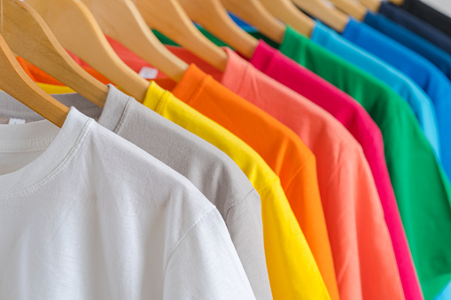 Primer plano de camisetas coloridas en perchas, fondo de ropa photo