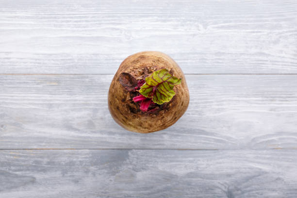 Fresh beetroot with leaves, whole raw beet on a gray wooden table. Food background. Top view. Close-up. Copy space.