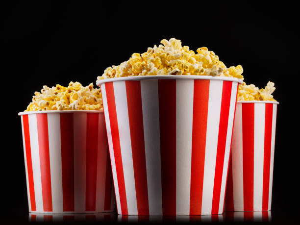 istock Paper striped buckets with popcorn isolated on black background 1170640355