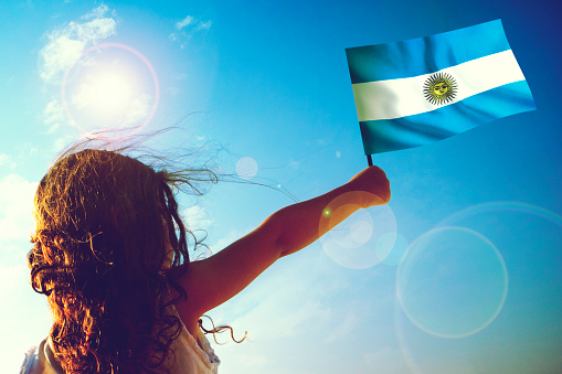 Little girl waving Argentinian Flag on sunny beautiful day