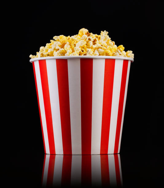 Paper striped bucket with popcorn isolated on black background