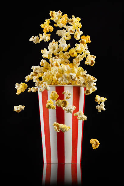 istock Flying popcorn from striped bucket isolated on black background 1170641576