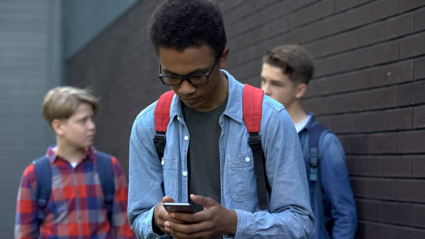 istock Black student reading offensive post in phone, boys mock behind, cyberbullying 1170641738
