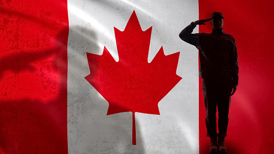 Silueta de soldado canadiense saludando contra la bandera nacional, reforma del sargento del ejército photo