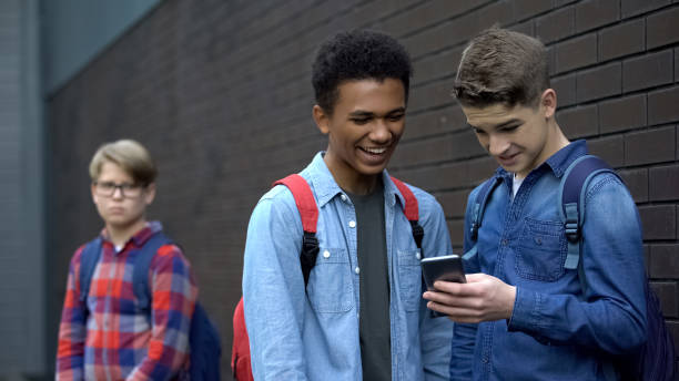 istock Two bully boys posting offensive video about upset guy behind, cyberbullying 1170641766