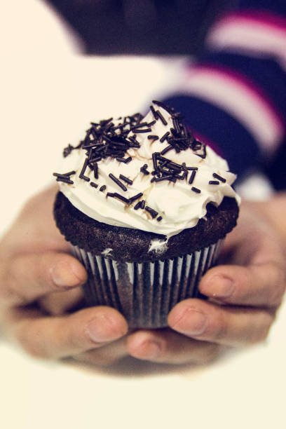 Girl holds a sweet cupcake on her hands. Front View.