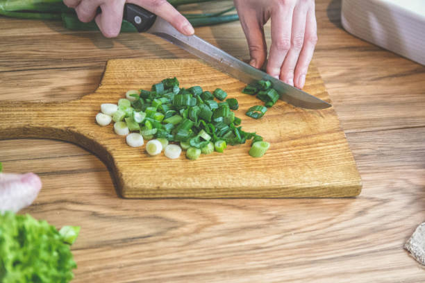 istock Female hand cutting green onions on board with knife 1170641929