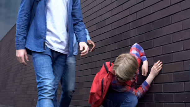 istock Weak junior student falling from punches, leaning against wall, school bullying 1170641948