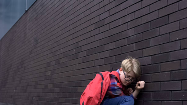 istock Scared schoolboy leaning against wall, hiding from bullying, intimidation 1170641952