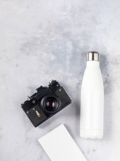 istock Eco friendly reusable bottle next to a vintage analog camera and notebook isolated on light gray concrete background. Flat lay. Top view. Copy space 1170656072