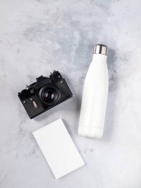istock Eco friendly reusable bottle next to a vintage analog camera and notebook isolated on light gray concrete background. Flat lay. Top view. Copy space 1170656077