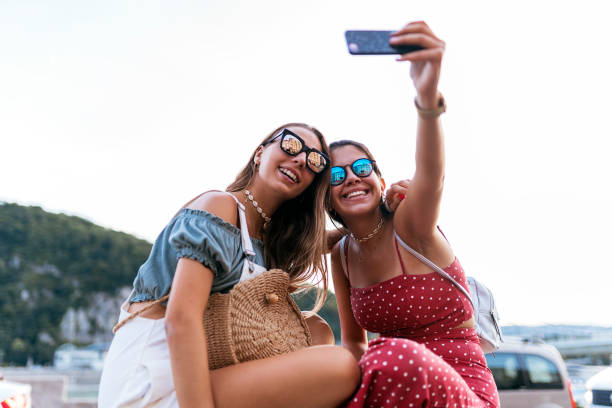 istock Cheerful women sitting on bridge and using cellphone 1170657385