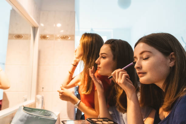 istock three young woman putting up make up in front of mirror 1170659315