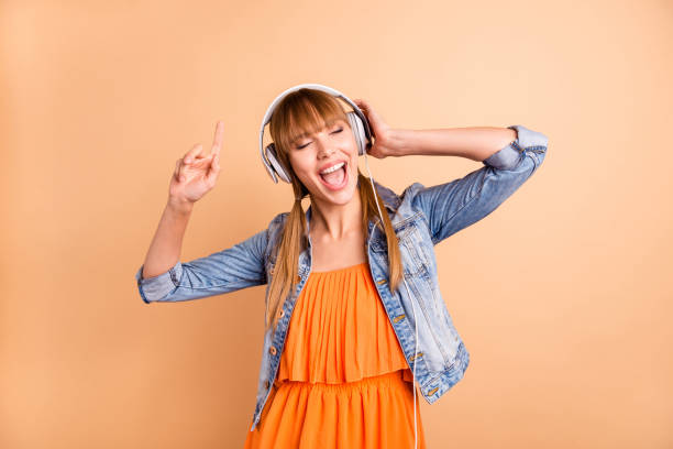 photo of pretty lady turn on earflaps singing loudly wear casual outfit isolated pastel beige background - bangs fashion model women elegance imagens e fotografias de stock