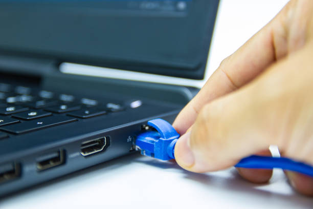 istock blue cable network connection to a Lan port of laptop computer on white table 1170665554