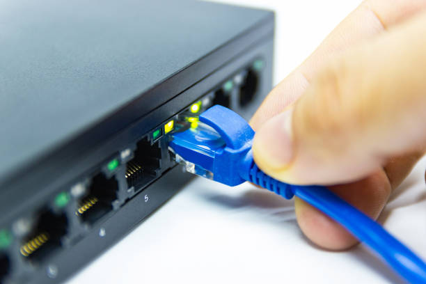 istock Hand of man holding The blue network cables connect port switch on white table 1170665746