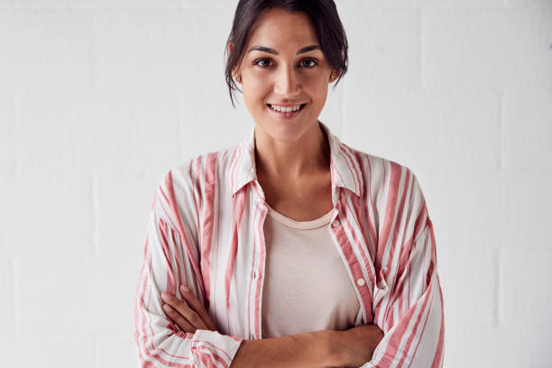 istock Portrait Of Smiling Casually Dressed Woman Standing Against White Brick Studio Wall 1170667798