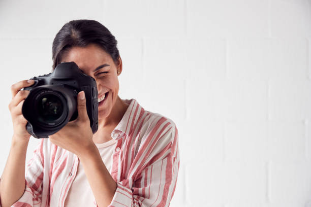 istock Female Photographer With Camera On Photo Shoot Against White Studio Backdrop 1170667832