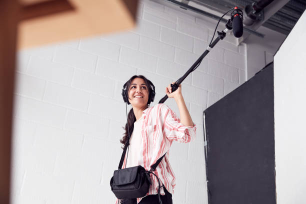 weibliche tonaufnahme hält mikrofon auf videofilmproduktion in white studio - toningenieur stock-fotos und bilder
