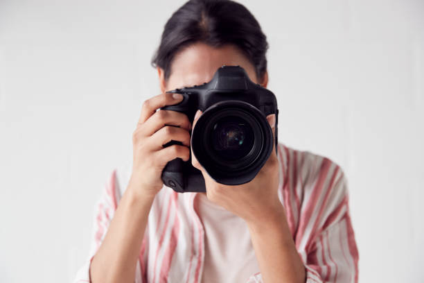 istock Female Photographer With Camera On Photo Shoot Against White Studio Backdrop 1170667875