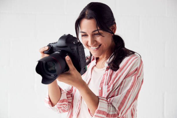 istock Female Photographer With Camera On Photo Shoot Against White Studio Backdrop 1170667893