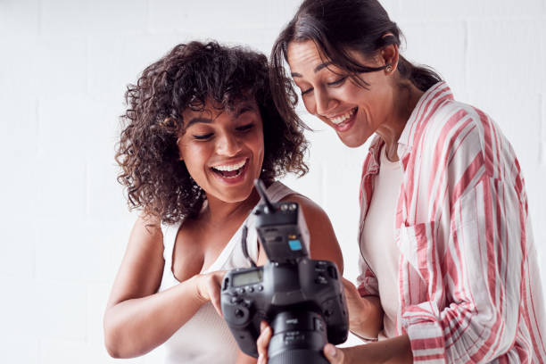 istock Smiling Female Photographer Holding Camera With Model In Studio Portrait Session 1170668232