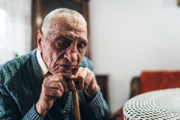 Thinking about life Older man with walking stick, leaning his head on it. Sitting and thinking about life. old man depressed stock pictures, royalty-free photos & images