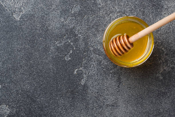 istock Liquid honey and honey stick on a gray background copy space. 1170674048