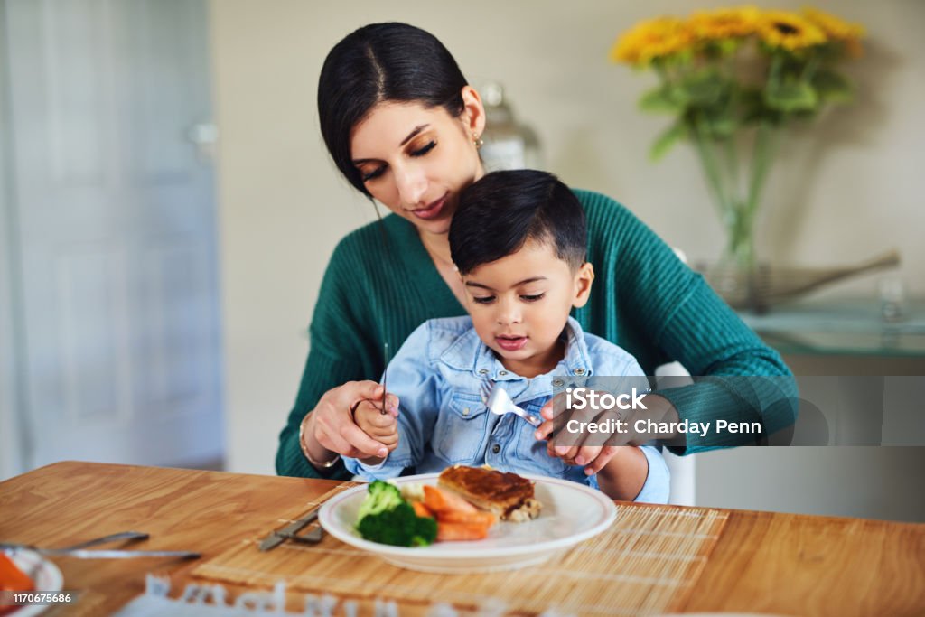 Teaching her little one about basic table manners Shot of a mother feeding her little son a meal at home Child Stock Photo