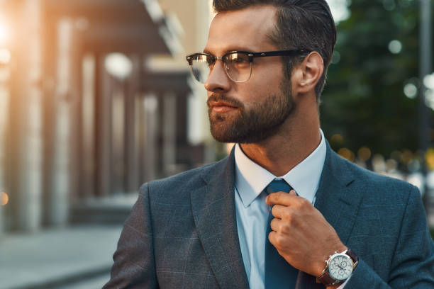 istock Great look. Confident businessman in full suit adjusting his tie and looking away while standing outdoors 1170677188