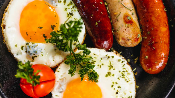 istock Fried eggs sunny side up served with sausage in a cooking pan 1170679124