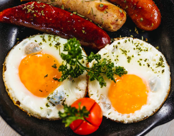 istock Fried eggs sunny side up served with sausage in a cooking pan 1170679268