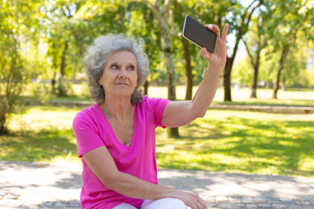 istock Excited old lady taking selfie in park 1170680443
