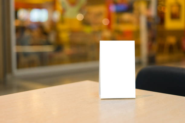 istock Mock up Label the blank menu frame in Bar restaurant ,Stand for booklets with white sheets paper acrylic tent card on wooden table cafeteria blurred background can inserting the text of the customer. 1170680459