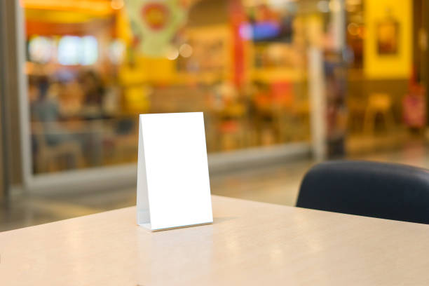 istock Mock up Label the blank menu frame in Bar restaurant ,Stand for booklets with white sheets paper acrylic tent card on wooden table cafeteria blurred background can inserting the text of the customer. 1170680465