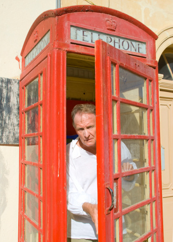 Man exiting a traditional English Phonebox