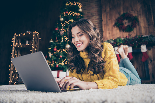 Photo of cute nice charming, attractive girl woring in eve of new year with her laptop wearing jeans denim yellow sweater