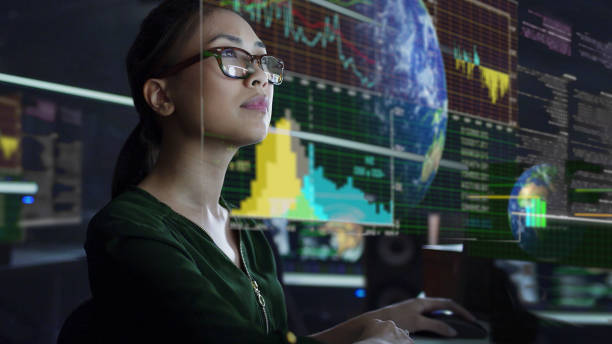 See through screen Stock photo of a young Asian woman looking at see through global & environmental data whilst seated in a dark office. The data is projected on a see through (see-thru) display. projection screen stock pictures, royalty-free photos & images